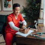 Man in scrubs at a desk in a furnished apartment