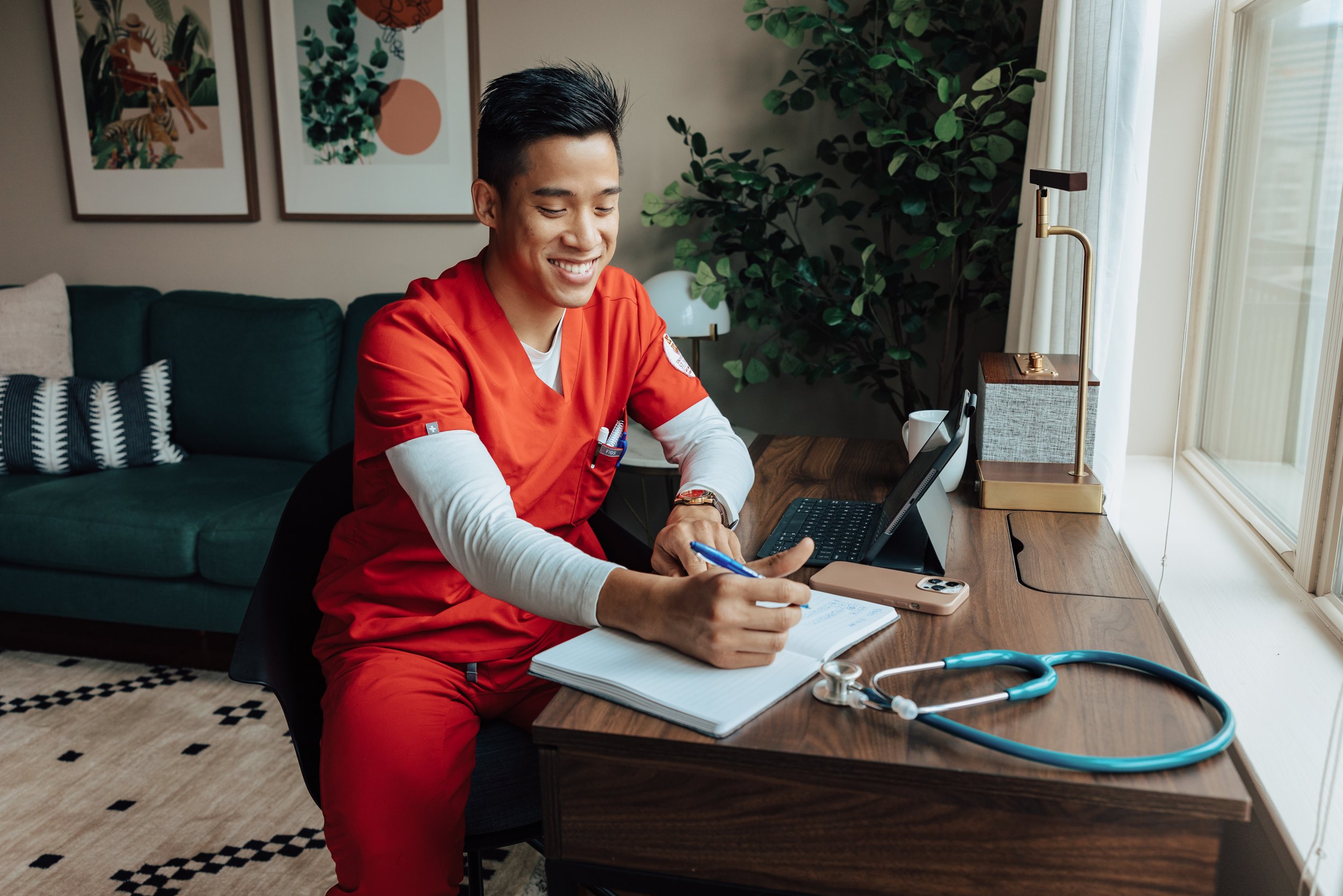 Man in scrubs at a desk in a furnished apartment