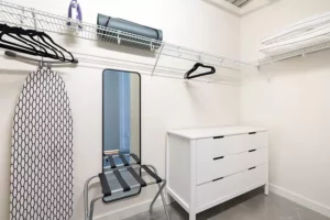 Closet with luggage rack, yoga mat, dresser, vacuum, full-length mirror and ironing board