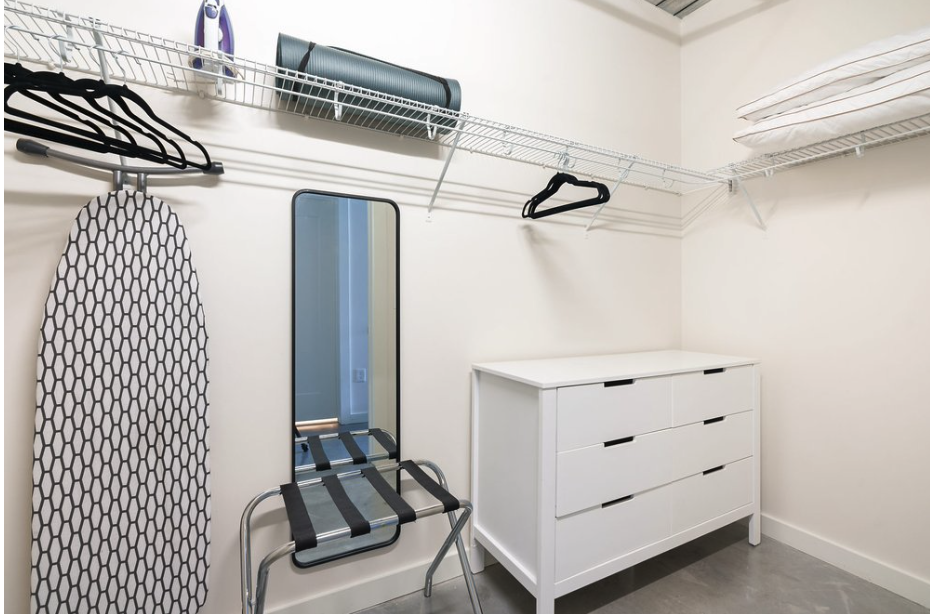 Closet with iron, ironing board, yoga mat, luggage rack and laundry bag