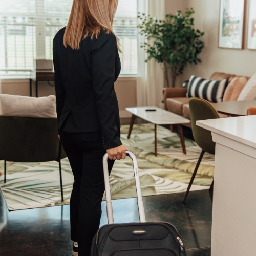 Image of a business person walking into Lodgeur corporate housing with their suitcase