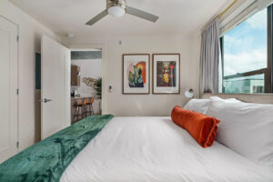Spacious bedroom with king-sized bed, white linens, modern art, and city views at Lodgeur's corporate apartments in Houston.