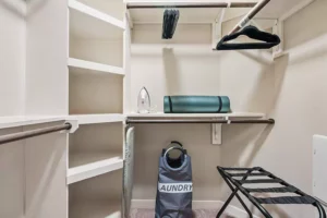 Closet with iron, ironing board, yoga mat, luggage rack and laundry bag