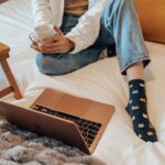 Woman on a bed with a laptop and coffee