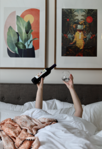 Woman in a plush king-sized bed holding wine