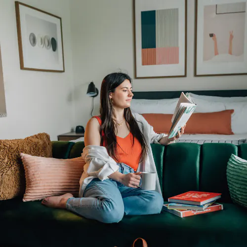 Image of a student sitting on a couch reading in a Lodgeur furnished apartment