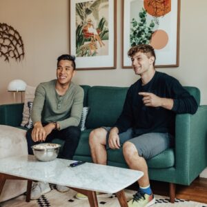 two interns watching TV in a furnished apartment