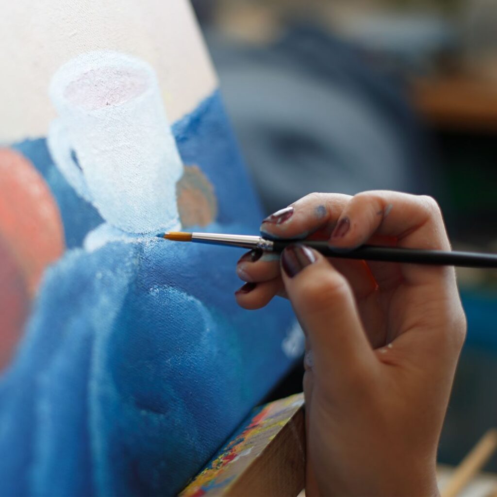 A painter creating art on canvas with a paintbrush.