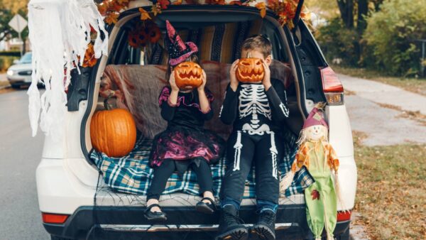 Kids holding their scary pumpkins at the back of the car for Halloween