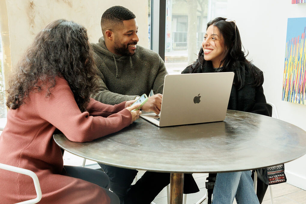 three young professionals at a table with a laptop