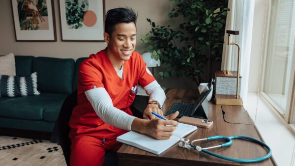 Man in scrubs at a desk in a furnished apartment