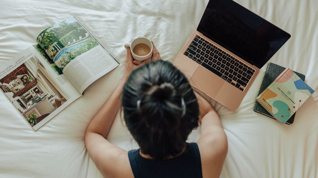 woman on a bed with a laptop and books