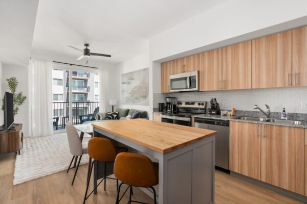 A wide shot of a kitchen with a kitchen island and bar stools at Lodgeur Energy Corridor