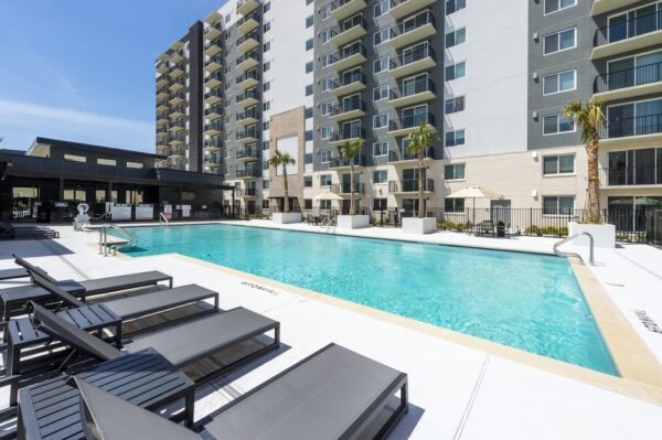 The swimming pool at Lodgeur Energy Corridor with sun loungers in the foreground and one of the apartment towers in the background